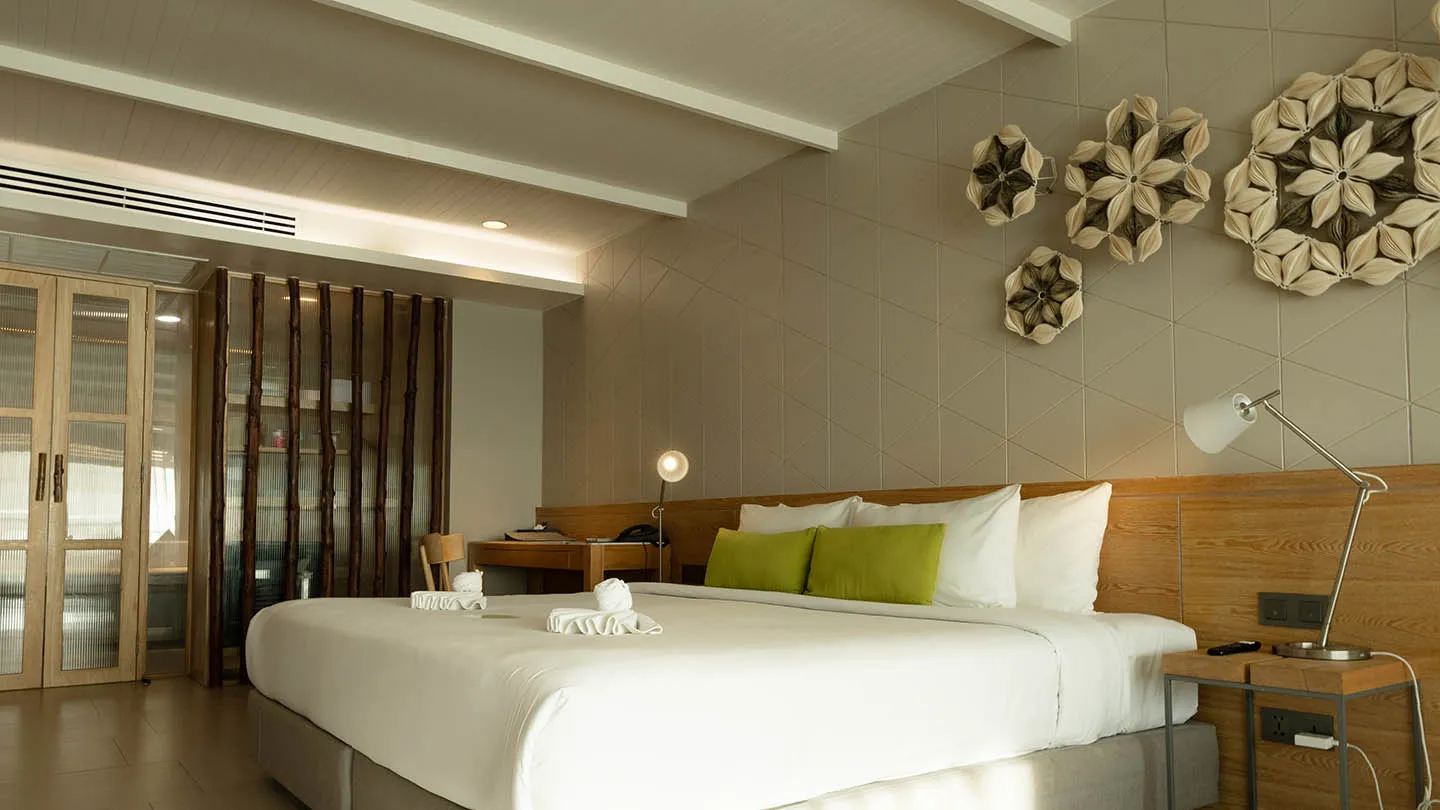 The bedroom features a plush king-sized bed with crisp linens and cushions, complemented by a functional writing desk for both comfort and convenience
