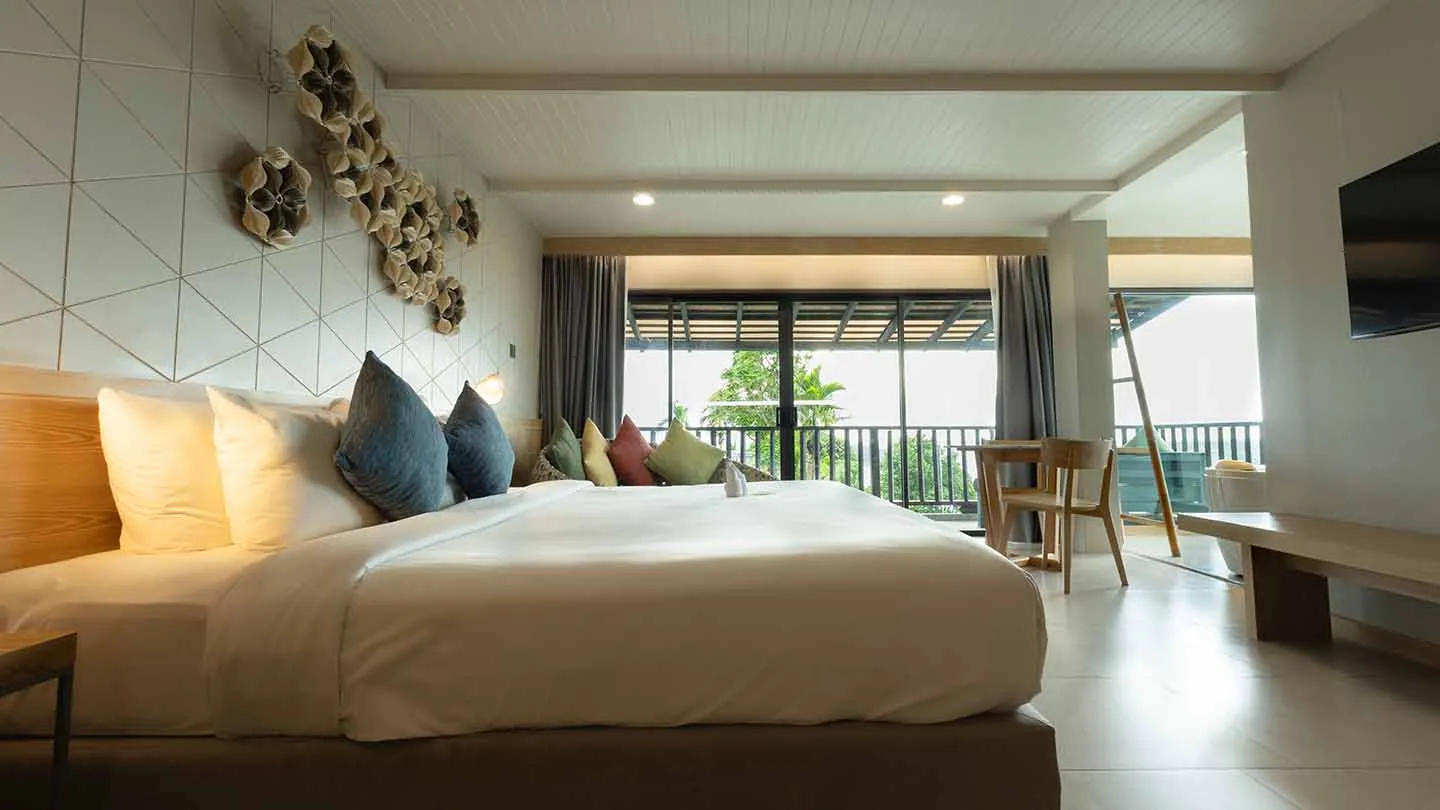 Honeymoon Suite featuring a spacious bed with white linens, a round daybed near a window to the outdoors, and scenic greenery views