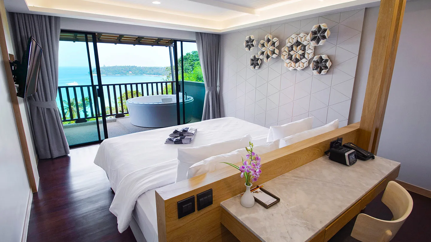 A spacious Junior Suite features a large bed, living area, desk, and private balcony with views, all styled with modern Thai decor and natural finishes