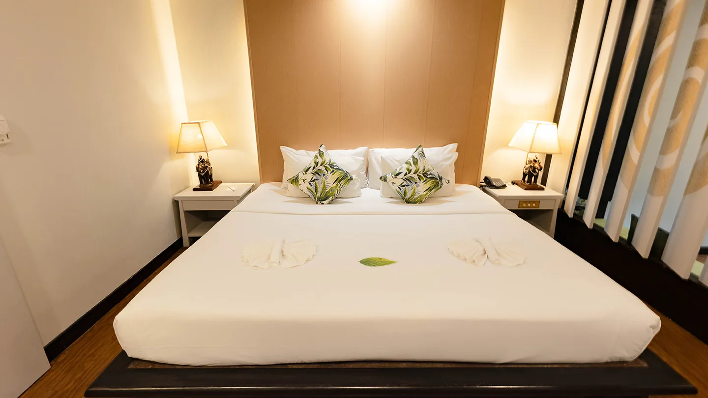 A stylish bedroom featuring a king bed with bedside tables and lamps, accented with earthy tones and warm wooden details
