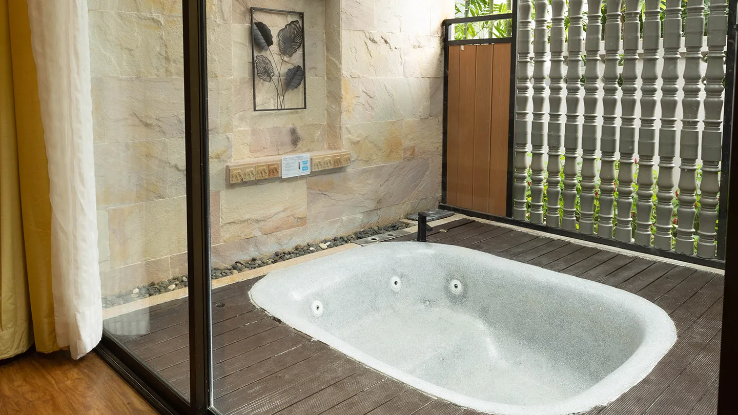 A luxurious bathroom with a stone wall, wooden details, and a spacious white sunken bathtub