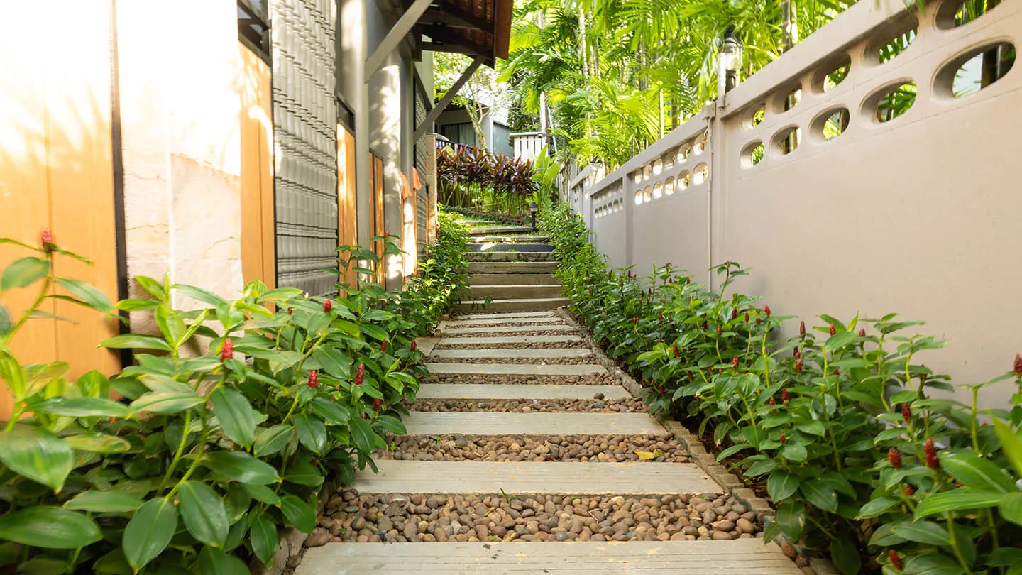 A hillside stone pathway with steps surrounded by dense tropical greenery within the resort’s garden area