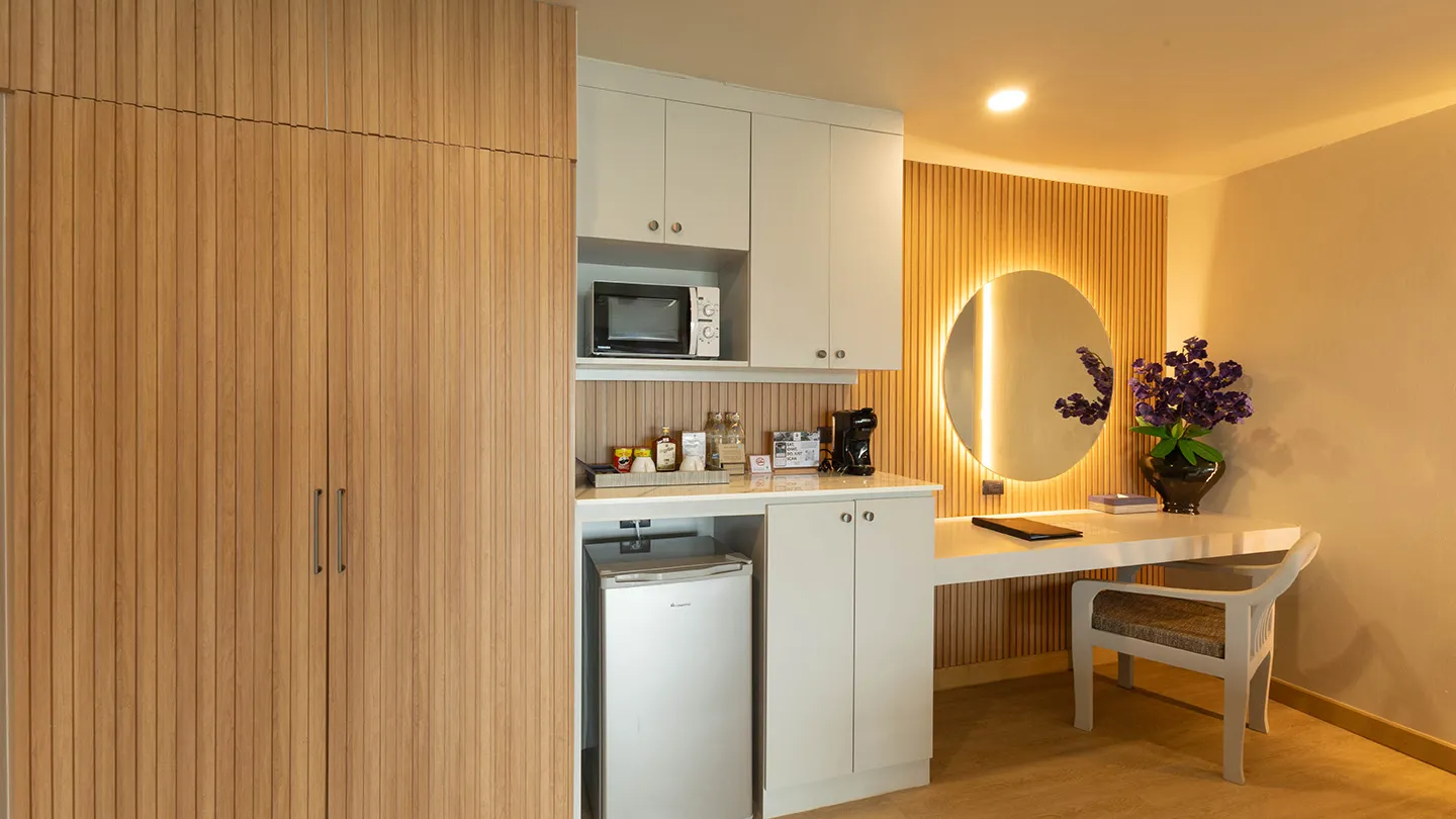 Built-in wooden cabinet with minibar, paired with a vanity and round mirror, showcasing contemporary decor in soft, muted tones