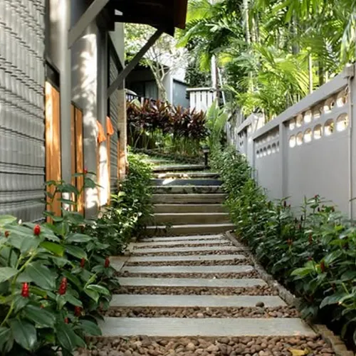 A hillside stone and gravel path with steps, surrounded by dense tropical greenery, likely part of the resort’s garden